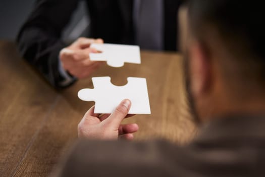 two businessmen put together a puzzle opposite each other
