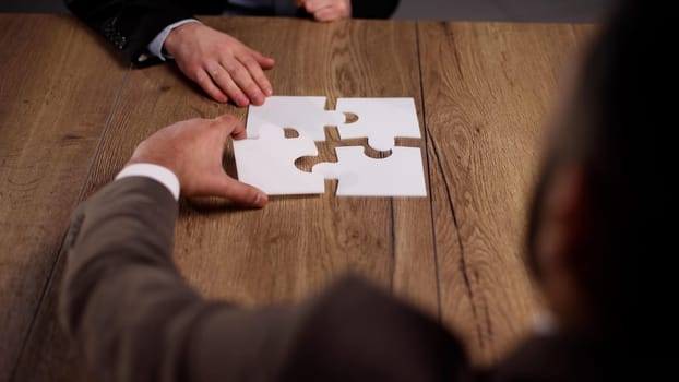close up.business partners putting together a puzzle ,sitting at office Desk