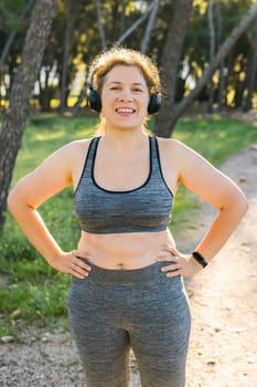 Fat woman and sports. Girl doing exercise for weight loss in the fresh air and laughing in camera after training.