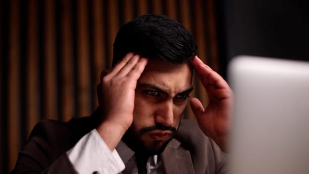 Tired man behind a computer screen from boring routine work in the office.