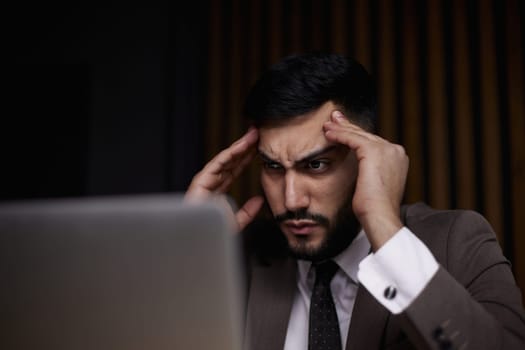 Businessman using a laptop while working late in his office