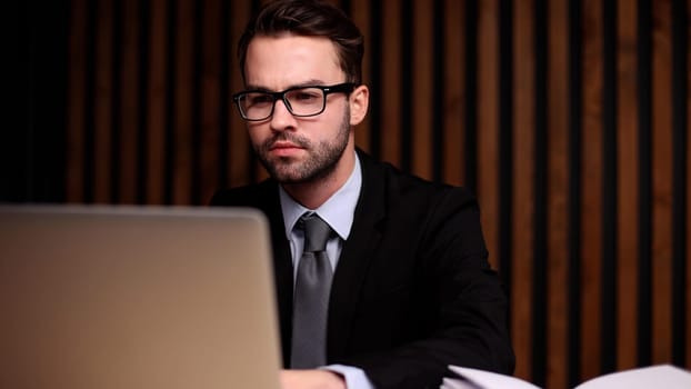 Shot of a young businessman using a computer at his desk in a modern office.