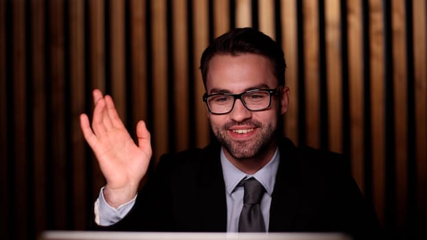 Young successful businessman waving his hand, greeting a colleague.