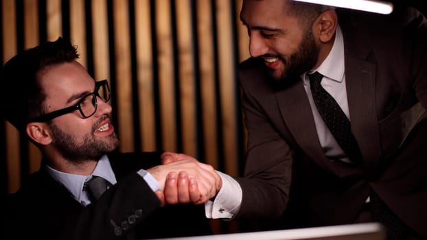 two men at the table shake hands