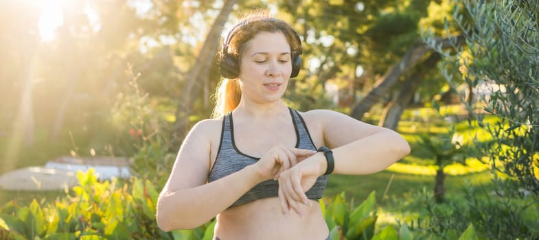 Young plus size woman with smart watch. Girl training in park. Woman with fitness tracker