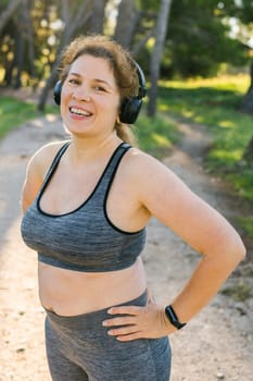 Fat woman and sports. Girl doing exercise for weight loss in the fresh air and laughing in camera after training.