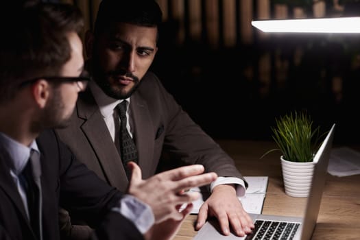 colleagues looking at the computer monitor in the night office