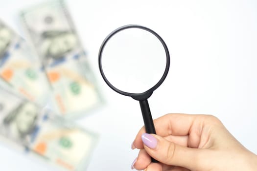 Selective focus. Magnifying glass and money - lies on american dollars on white, business background. The concept of poverty and the search for money, the search for earnings. High quality photo