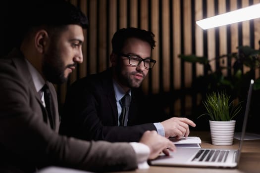 man looks at the laptop screen and asks other people about something