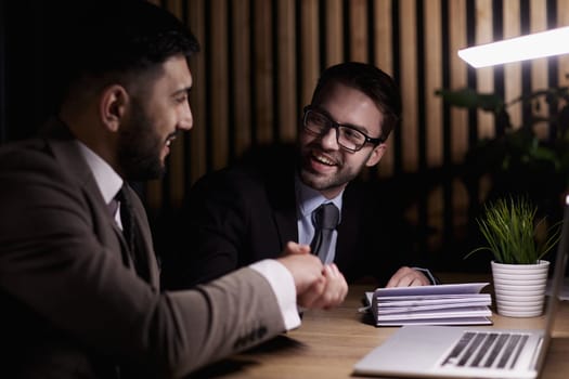 Two positive confident businessmen shaking hands over meeting table after negotiation,