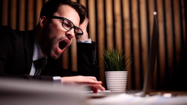 employee stretching and yawning during break in office after work done.