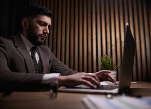A man of Spanish appearance works at the office with a laptop