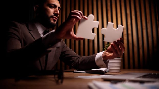 businessman assembling puzzle on table in office
