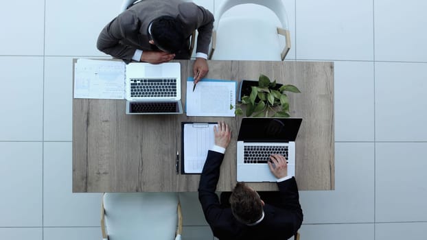 two businessmen sitting on a chair and watching something on a laptop