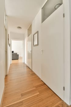 an empty room with wood flooring and white door leading to the living area on the left is a couch