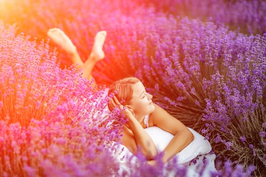 A middle-aged woman lies in a lavender field and enjoys aromatherapy. Aromatherapy concept, lavender oil, photo session in lavender.