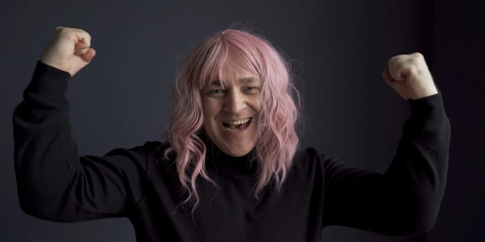 Positive man in a pink wig rejoices in success. Close-up