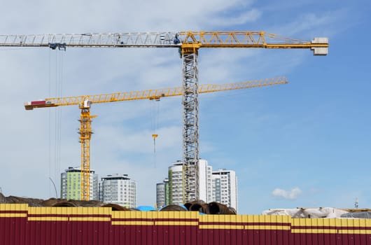 Construction cranes against the blue sky. Bottom view. Building concept.