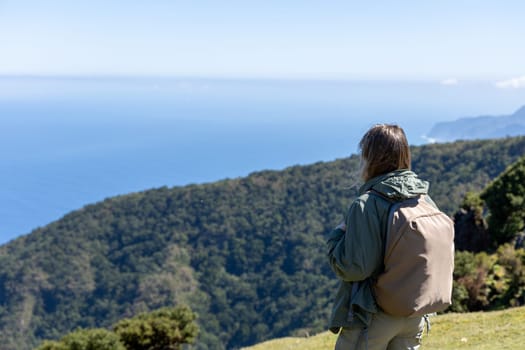 A woman with a backpack taking in the majestic view of a coastal landscape