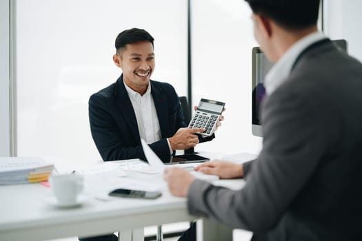 Two business people meeting to talking or discuss marketing work in workplace using paperwork, calculator, computer to work.