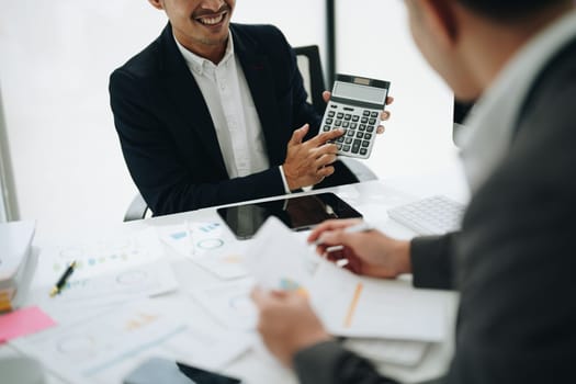 Two business people meeting to talking or discuss marketing work in workplace using paperwork, calculator, computer to work.