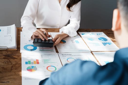 Accountant checking financial statement or counting by calculator income for tax form, Business woman sitting and working with colleague discussing the desk in office. Audit concept.