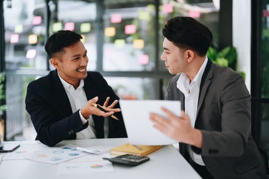 Two business men meeting to talking or discuss marketing work in workplace using paperwork, calculator, computer to work