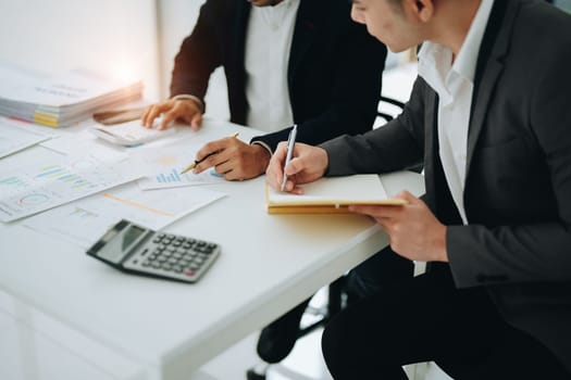 Two business men meeting to talking or discuss marketing work in workplace using paperwork, calculator, computer to work