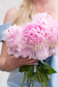 bride in a blue wedding dress with a bouquet of pink peonies, pastel paradise, floral background, complementary color combination. High quality photo