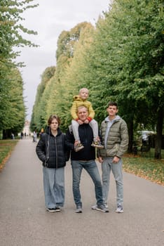 Happy family - Father with three children together in autumn park. Making it a day of fun. Parents spending time with their children outside.