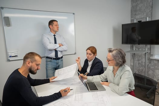 Caucasian man leading a presentation to colleagues at a white board