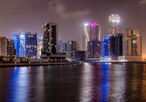 Night view of skyline of apartments buildings alongside canal in Business Bay