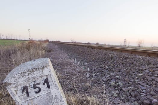 Milestone next to rural railroad tracks. High quality photo