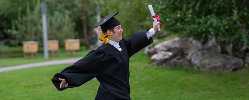 Caucasian woman in graduate gown dancing for joy outdoors