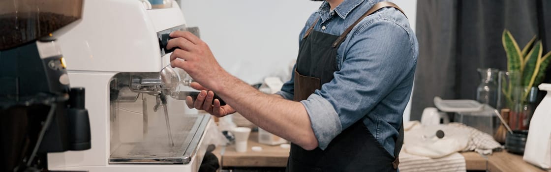 Handsome barista washes a coffee machine and holds a coffee tank in cafeteria