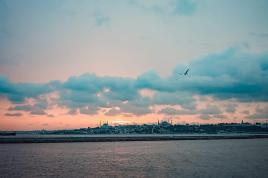 Istanbul at sunset, Turkey. Tourist boat sails on Golden Horn in summer. Beautiful sunny view of Istanbul waterfront with old mosque. Concept of travel, tourism and vacation in Istanbul and Turkey. Turkiye.