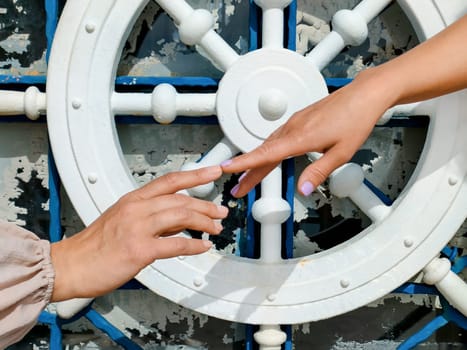 Two female hands try to touch each other with their index fingers against background of a symbolic steering wheel, concept of human relationships, partnership and unity, close-up