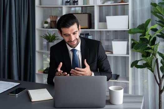 Professional businessman in black suit, present financial data or BI paper via laptop during online meeting. Remote work concept with virtual meeting presentation of effectiveness remote work. Fervent
