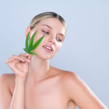 Alluring beautiful woman model portrait holding green leaf as concept for cannabis skincare cosmetic product for skin freshness treatment in isolated background.