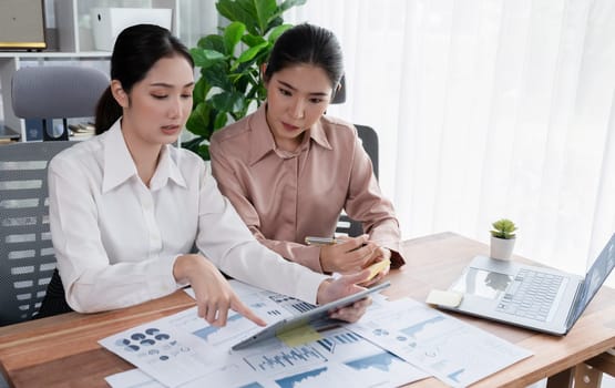 Analyst team colleague discuss financial data on digital dashboard, analyzing charts graph display on laptop and tablet screen. Modern office use business intelligence to plan marketing. Enthusiastic