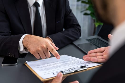 Closeup business deal meeting, businessman carefully reviewing terms and condition of contract agreement papers in office. Corporate lawyer give consultation on contract deal. Fervent