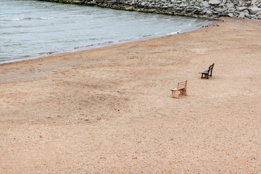 Two wooden benches stand on the beach with sand. A place of rest, reflection and solitude