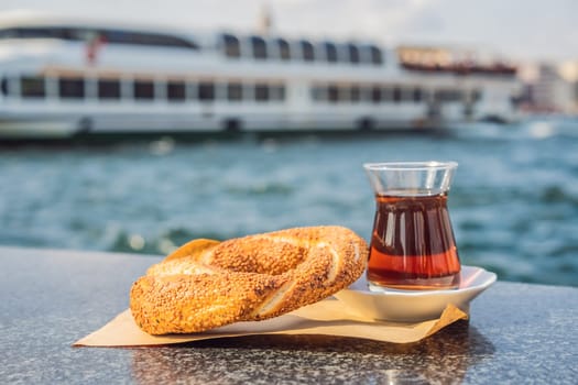 A glass of Turkish tea and bagel Simit against golden horn bay in Istanbul, Turkey. Turkiye.