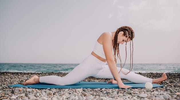 Woman yoga sea. Well looking middle aged woman with braids dreadlocks in white leggings and tops doing stretching pilates on yoga mat near sea. Female fitness yoga routine concept. Healthy lifestyle