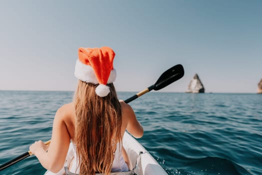 Woman in kayak back view. Happy young woman with long hair floating in transparent kayak on the crystal clear sea. Summer holiday vacation and cheerful female people relaxing having fun on the boat