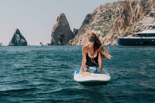 Close up shot of beautiful young caucasian woman with black hair and freckles looking at camera and smiling. Cute woman portrait in a pink bikini posing on a volcanic rock high above the sea