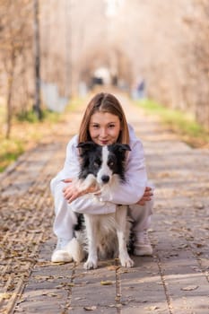 Caucasian woman hugging border collie in autumn park. Portrait of a girl with a dog