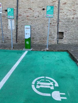 Loreto, Ancona, Italy - April 2023 Charging station for electric vehicles near the walls of Basilica sign and parking space for 2 cars