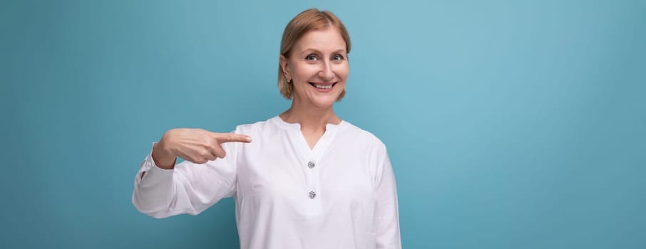 well-groomed blonde middle-aged woman in a white blouse on a studio background with copyspace.