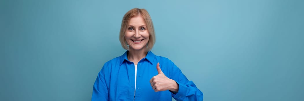 adult woman with blond hair smiling on blue background with copy space.